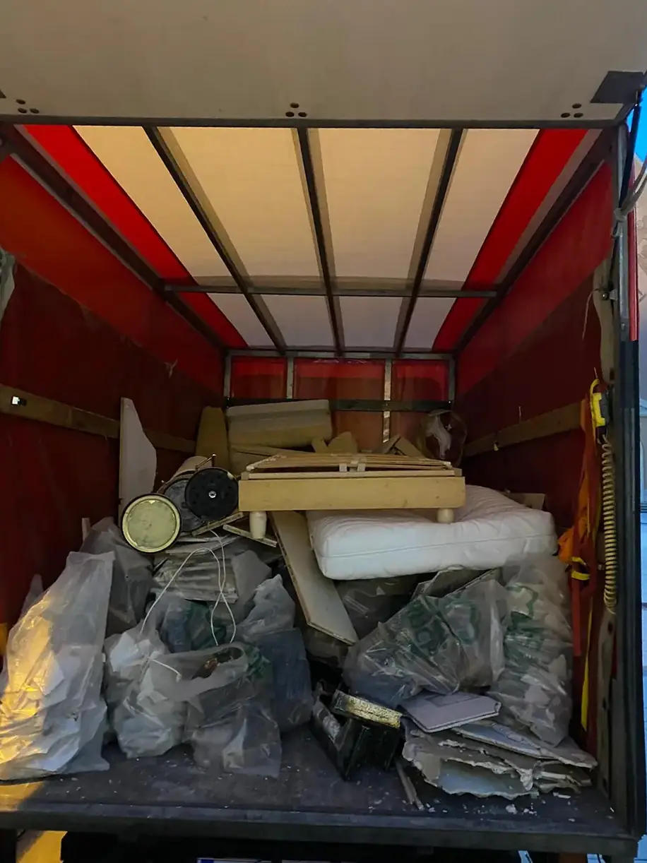 Die Ladefläche des roten Lkw mit Säcken, einer Matratze und Möbelteilen
