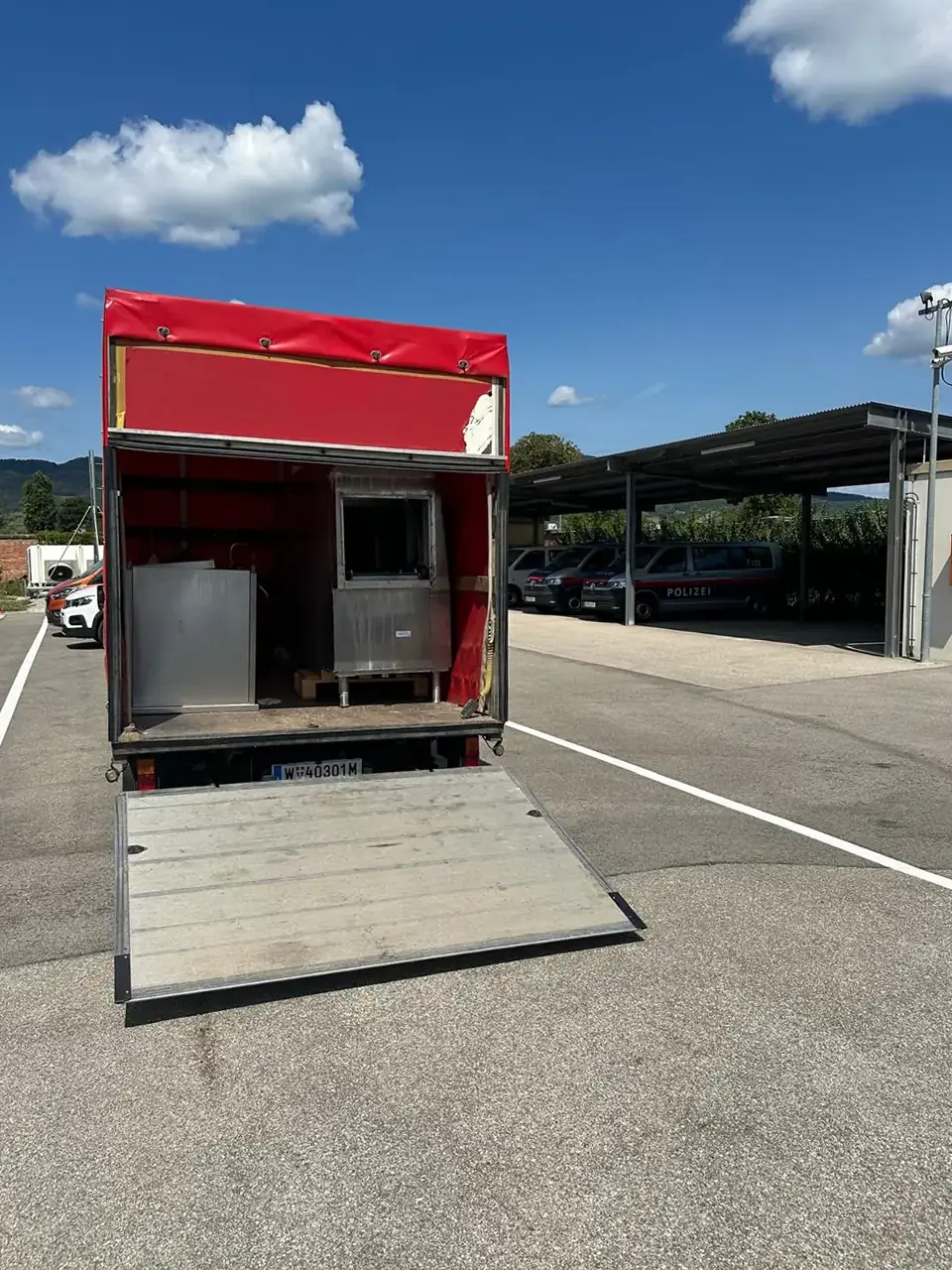 Der rote Lkw von Entrümpelung Bärenstark mit heruntergelassener Ladebordwand